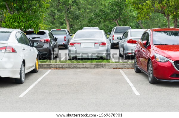 Cars\
parking in asphalt parking lot with trees forest background, empty\
space for car parking. Outdoor parking lot with green environment.\
nature travel transportation technology\
concept\
\
