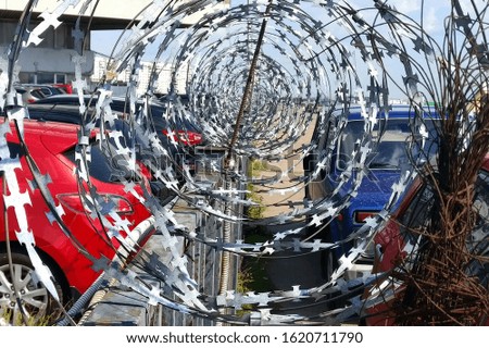 Cars in the parking lot on either side of the barbed wire