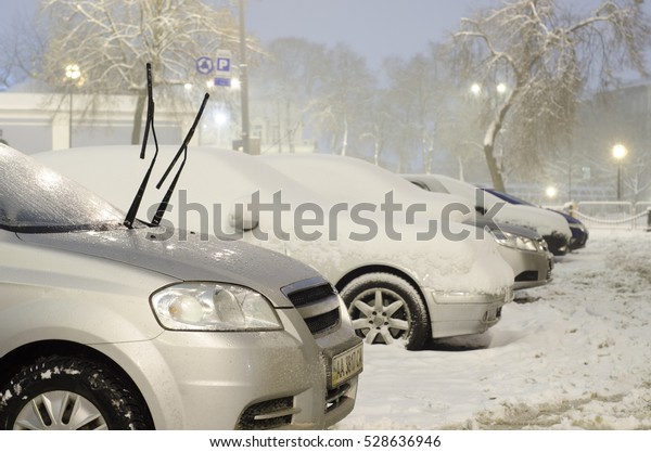 Cars in\
the parking lot in the winter blizzard\
night