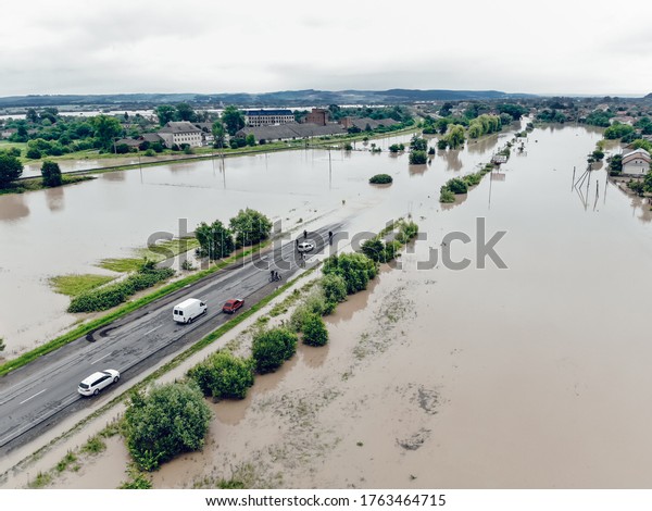 Cars and people cannot cross a\
flooded road. Aerial view of the flooded road, streets and houses\
in the city. Global catastrophe, climate change, flood\
concept