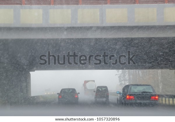 Cars in\
the rain on the street entering the\
viaduct