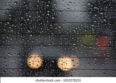 A car's rear window covered with rain drops. View of traffic thru the rear window during a rainy day of spring season in Bakersfield, CA, March 2018. 