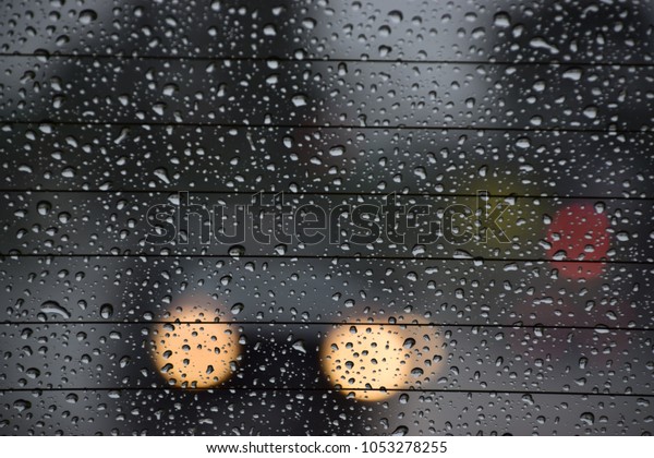 A car\'s rear window covered with rain drops.\
View of traffic thru the rear window during a rainy day of spring\
season in Bakersfield, CA, March 2018.\
