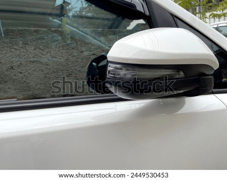 The car's rearview mirror folds with a round oval light shape