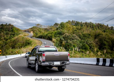 Автомобили, идущие по красивой дороге вдоль горы, вид сзади на пикап на волнистой дороге
