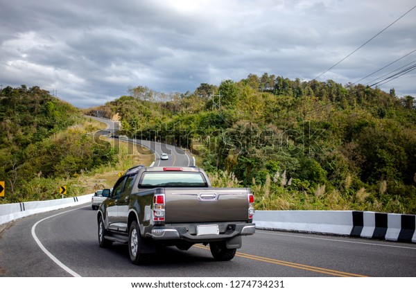 山に沿った美しい道を走る車 波打った道を走るピックアップトラックの背面 の写真素材 今すぐ編集