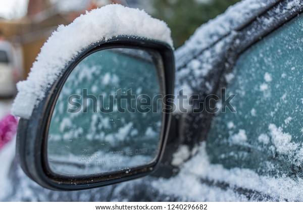 Car\'s\
side view mirror of a modern car covered  with\
snow