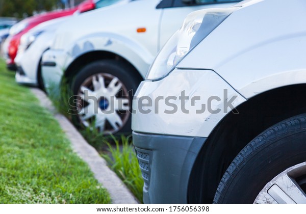 Cars are standing at the side of the\
road, with a green lawn, parked, close-up, side\
view.