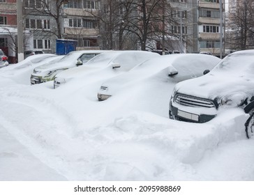 Cars standing in the snow. A snowdrift on the car. Heavy snowfall covered cars with snow. Snow-covered cars.