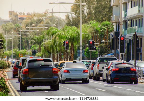 cars stopped at a red traffic\
light signal in the summer hot midday with a shallow depth of\
field