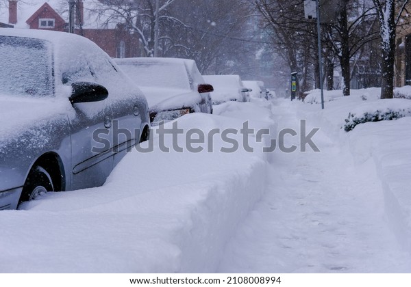 Cars stranded in deep\
snow on sidewalk
