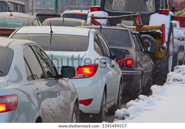 cars stuck in traffic on a winter street during\
a snowfall