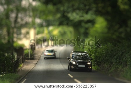 Cars traveling in the tunnel of trees. Typical Devonian road. Miniature Effect.