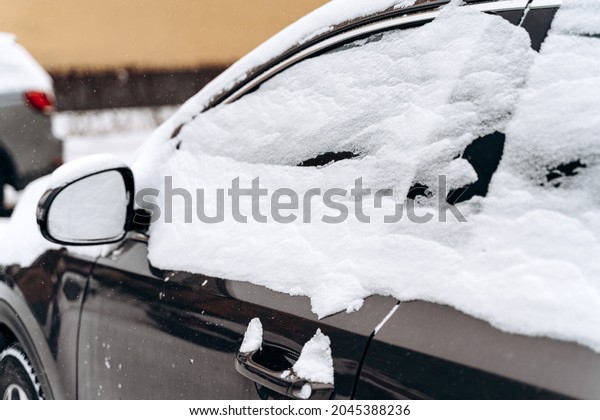 Cars under the snow after a snowfall. Cropped\
view of the snow on the roofs, windows and hoods of car. Snowy\
winter, lots of snow\
concept