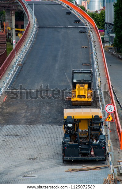 Cars used for repairing of a\
bridge  highway. Laying of an asphalt with a yellowhigh press\
roller