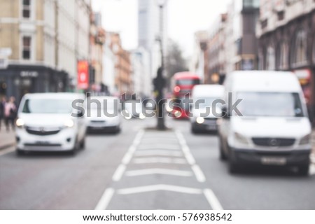 Cars, white vans driving on a road, London, street, blurred background, city, busy.