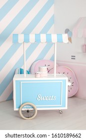 Cart With Candy Bar. Children Zone With Sweets: Lollipops, Ice Cream And Candy Bar. Children Room With Blue Stripe Background. Candy Stall Photo Zone.  Decorated Room For A Birthday. Holiday Decor