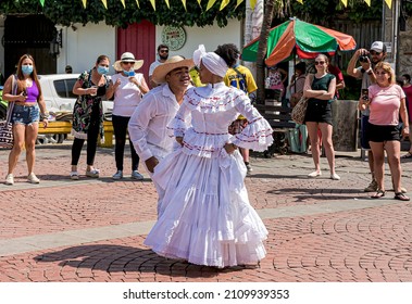 Cartagena, Bolívar, Colombia; 11- 11- 2021: Beautiful and enthusiastic couple dressed in white dance in the square communicating joy to the audience.