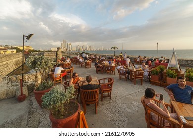 Cartagena, Colombia - May 11 2022: Tourists And Local People Enjoy A Drink At The Famous Café Del Mar On The Fortification Of Cartagena Colonial Old Town By The Caribbean Sea In Colombia At Sunset