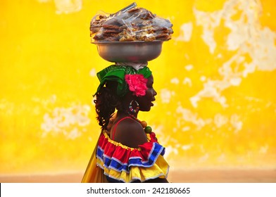 CARTAGENA DE INDIAS, COLOMBIA - JUNE 15, 2014: Colombian woman in Cartagena de Indias with the traditional dress. In Colombia is usual to transport fresh fruit and food on the head.