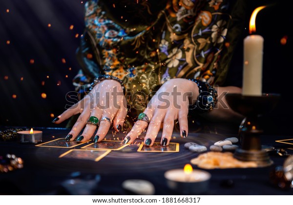 Cartomancy. A\
fortune teller reads Tarot cards. On the table are candles and\
fortune-telling objects and sparks. Hands close up. The concept of\
divination, astrology and\
esotericism