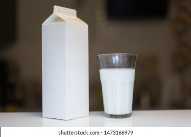 Carton Box And Glass Of Milk On Table In Kitchen