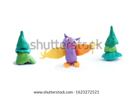 
Cartoon bat figure with spread fingers of orange and violet color and two plasticine  trees. Isolate on a white background.
