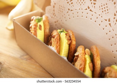 Cartoon Box With Delicious Lemon Ice Cream Cookie Sandwiches On Wooden Table, Closeup