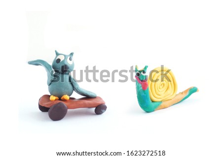 Cartoon plasticine figure owl on a skateboard and a plasticine snail. Isolate on a white background.
