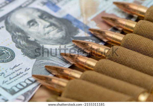 Cartridges with bullets in a bandolier, dollar\
bills. close-up, selective focusing. Concept: sale of weapons under\
lend-lease, assistance with weapons, mercenary work in the army,\
the war in Ukraine.