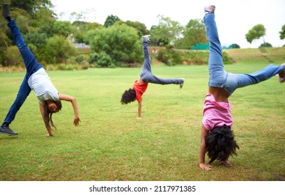 Cartwheel fun. Three young children doing handstands in the park.