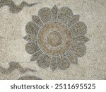 Carved flower medallion on the grunge cement floor, flower shape with thai Buddhism influence.