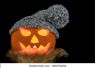 Carved halloween pumpkin with scarf and knitted hat isolated on a black background