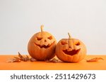 Carved pumpkins for Halloween, autumn leaves and acorns on color background