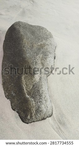 Carved stone object with rounded figure-like shape on light surface