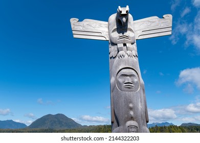 Carved totem pole in the beautiful Tofino with Meares Island in the background, a popular destination in Vancouver Island, Canada