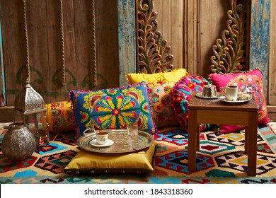 carved wood design pillows embroidered with fluorescent colors in front of the wall oriental corner turkish coffee presentation