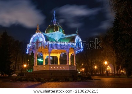 Carved wooden romantic gazebo - Altanka - symbol of Sumy city, Ukraine. Scenic night view of gazebo decorated and illuminated with garlands. Sumy is a popular travel destination in Ukraine