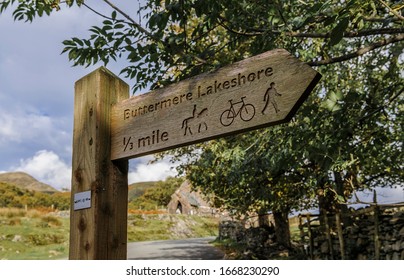 Carved Wooden Sign Pointing To Path Around Lake Buttermere In The English Lake District Showing Suitablability For Horse Riding, Cycling And Walking.