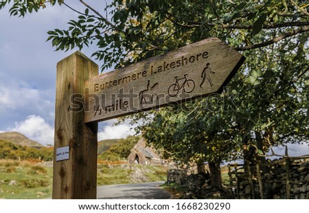 Carved wooden sign pointing to path around lake Buttermere in the English Lake District showing suitablability for horse riding, cycling and walking.