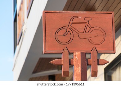 A Carved Wooden Sign Showing A Bicycle For Directions
