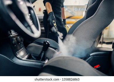 Carwash, worker cleans seats with steam cleaner