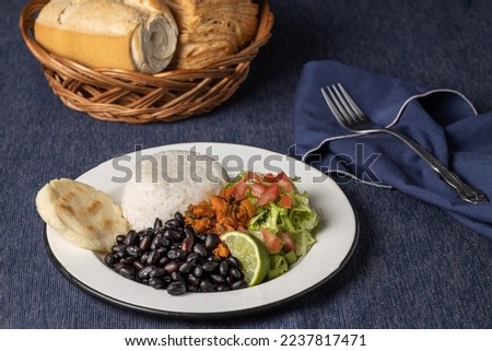 Casado, typical Costa Rican dish with rice, beans and vegetables on blue tablecloth.