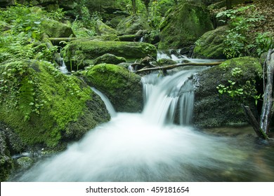 Cascade Falls Over Mossy Rocks In Deep Forest