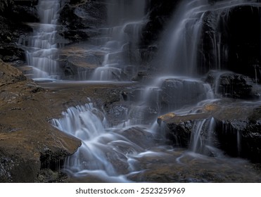 Cascading mountain stream flowing over rocks and cliff ledges as it meanders down into the valley - Powered by Shutterstock