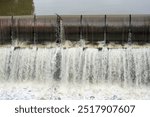 Cascading water over a dam spillway with a strong flow creating a rushing waterfall effect. Water management, engineering and hydropower. High quality photo