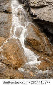 A cascading waterfall flows down a sheer rock face from a mountaintop. Shirlak Waterfall, Altai, Siberia, Russia.