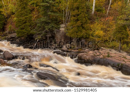 A cascading waterfall in the woods during autumn.