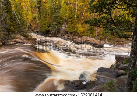 A cascading waterfall in the woods during autumn.
