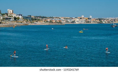 Cascais, Portugal - Sept 29, 2018: Persons enjoying stand up paddle at Cascais Bay during the summer with Estoril coastline in the background